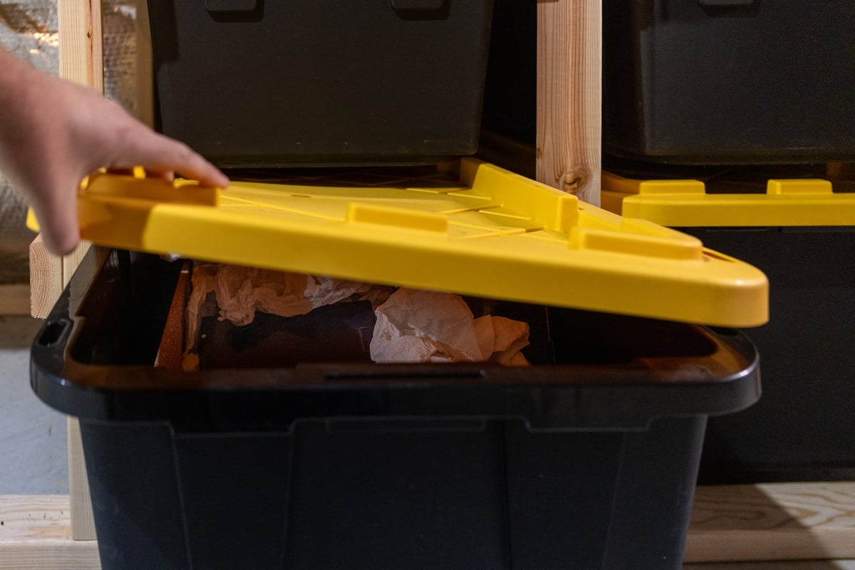 A person closes a large Tote Packers storage bin removed from shelving